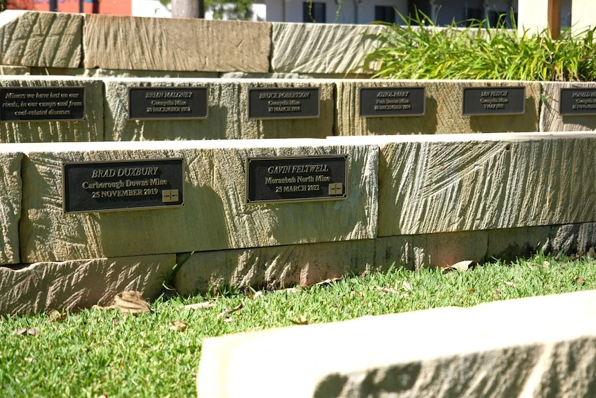 Sandstone blocks with plaques, close up of Gavin Feltwell, green grass