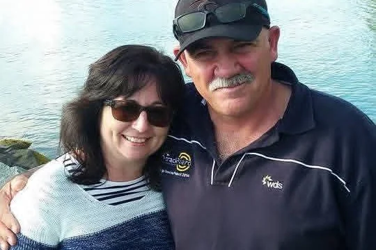 Man and woman armed around each other, taken on holiday smiling with lake in background, winter time, 