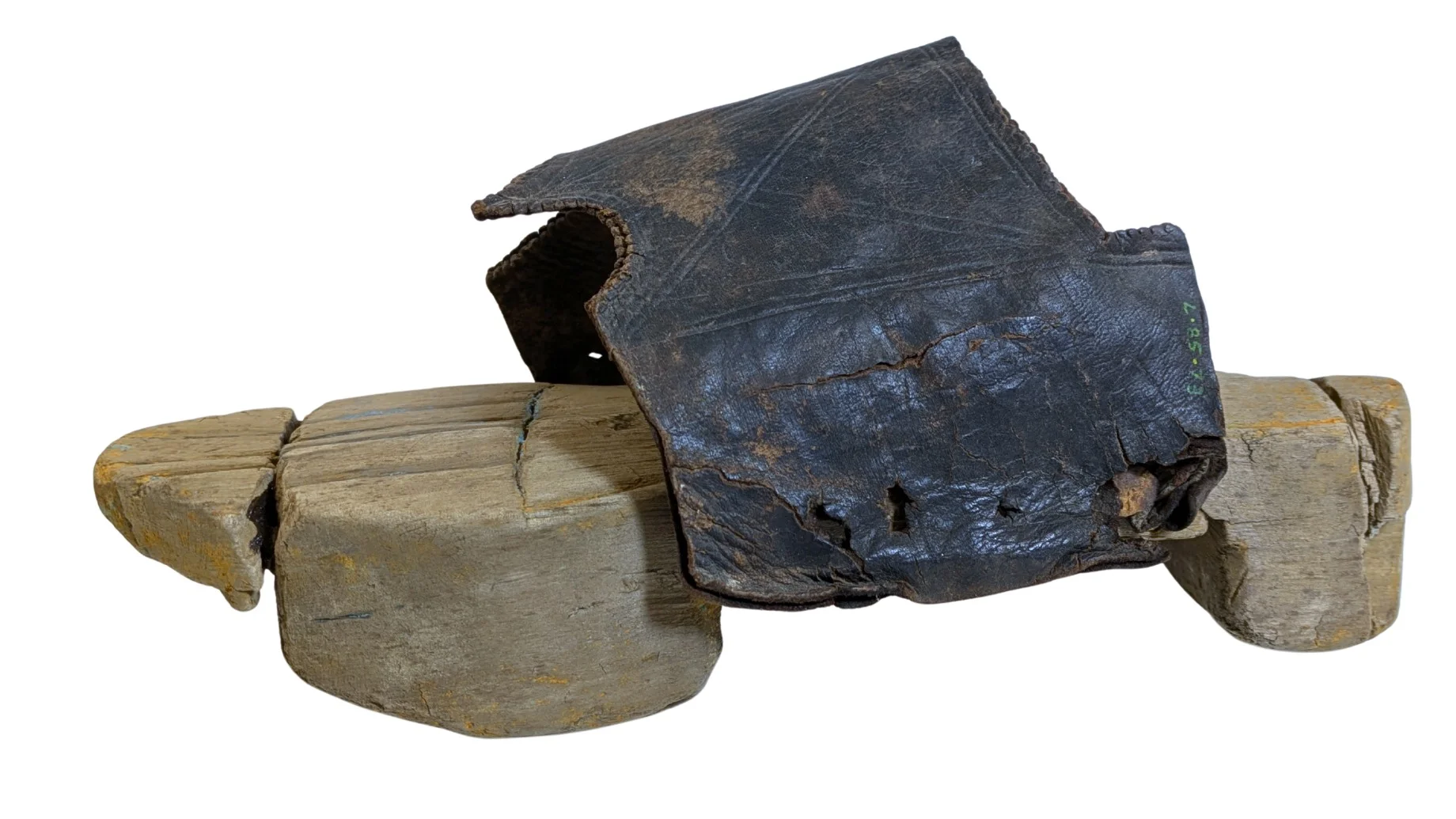 A wooden shoe heel is seen tied to a leather strap all against a white background