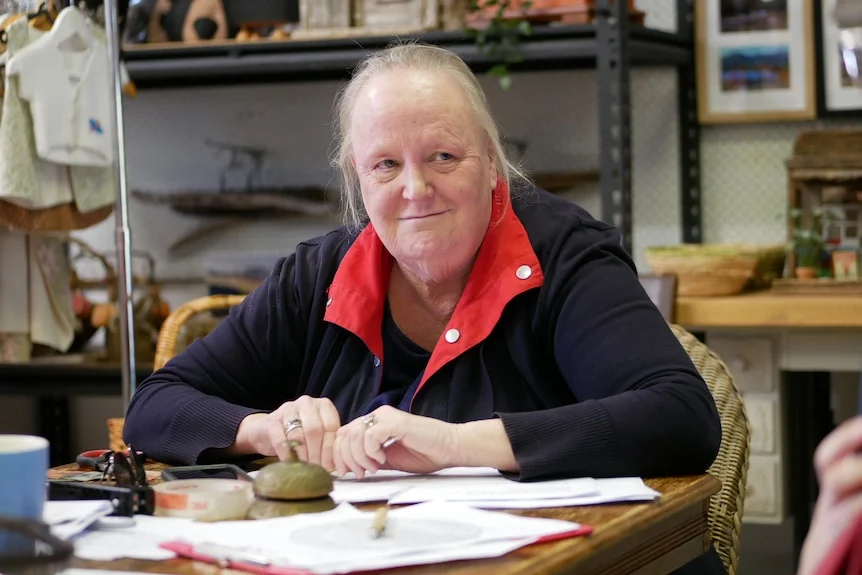 Debbie is in a black and red jumper, smiling to a friend