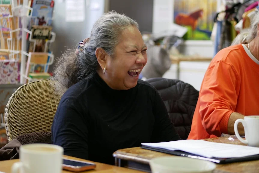 A lady in black laughing and smiling during a meeting