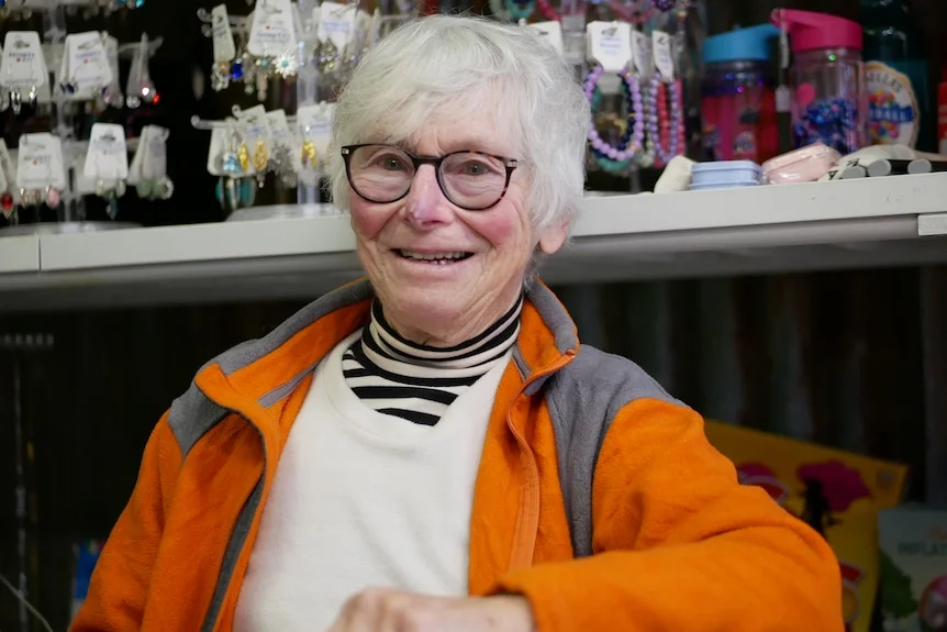Di is smiling at the camera in an orange jumper