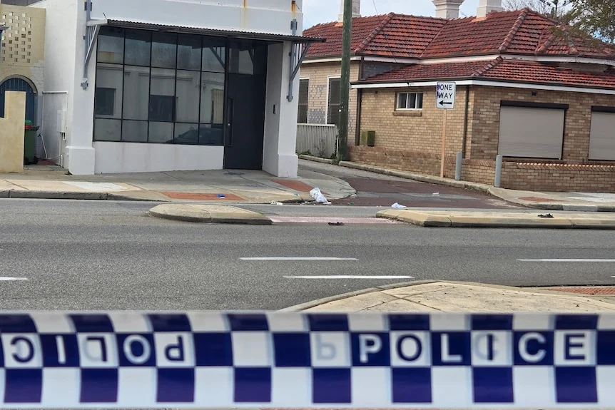 Police tape in the foreground of the photo with houses in the background