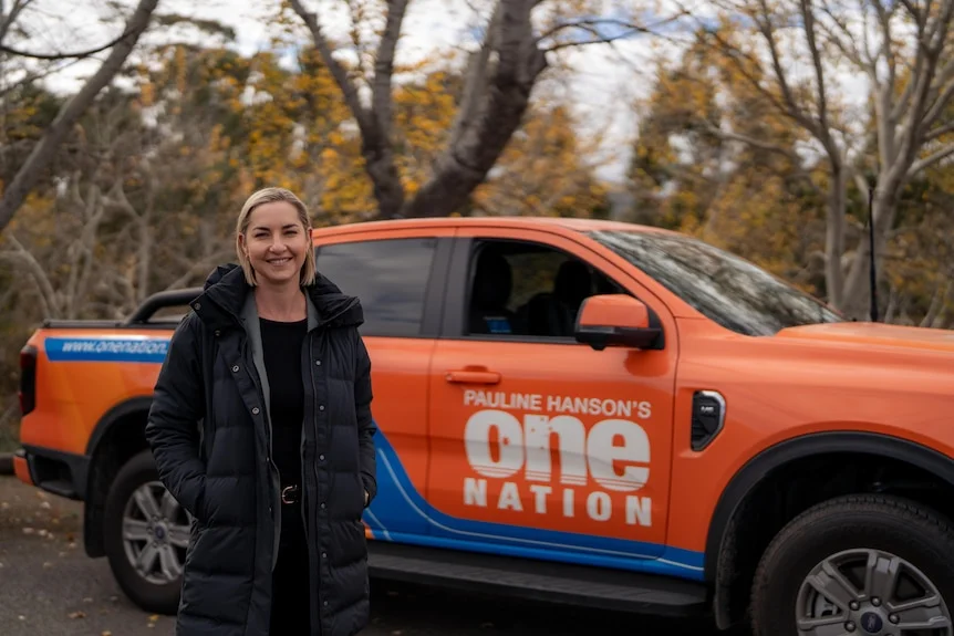 Woman stands with orange car