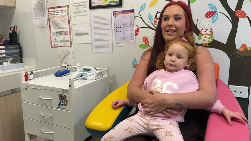 A mother with dyed red hair on a chair with a toddler with red hair on the lap