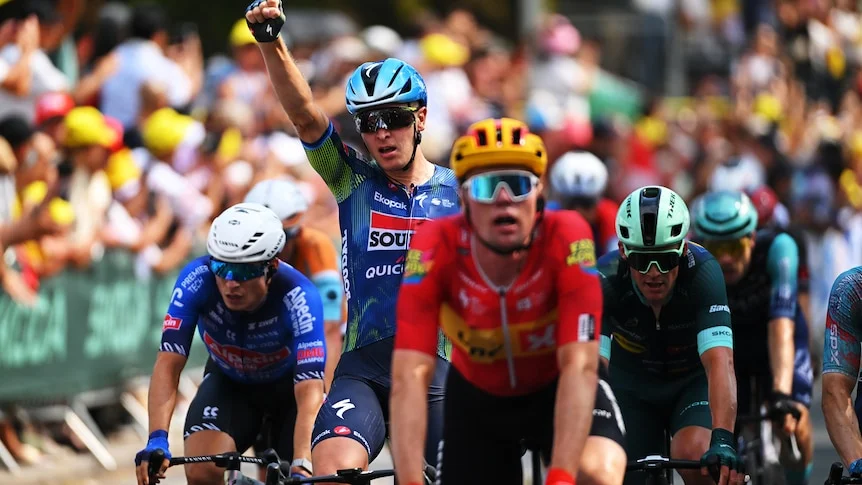 Tim Merlier raises his right fist in celebration