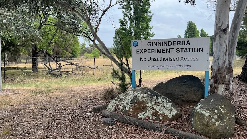 A sign that reads "CSIRO Ginninderra Experiment Station" outside a property with a chain fence.