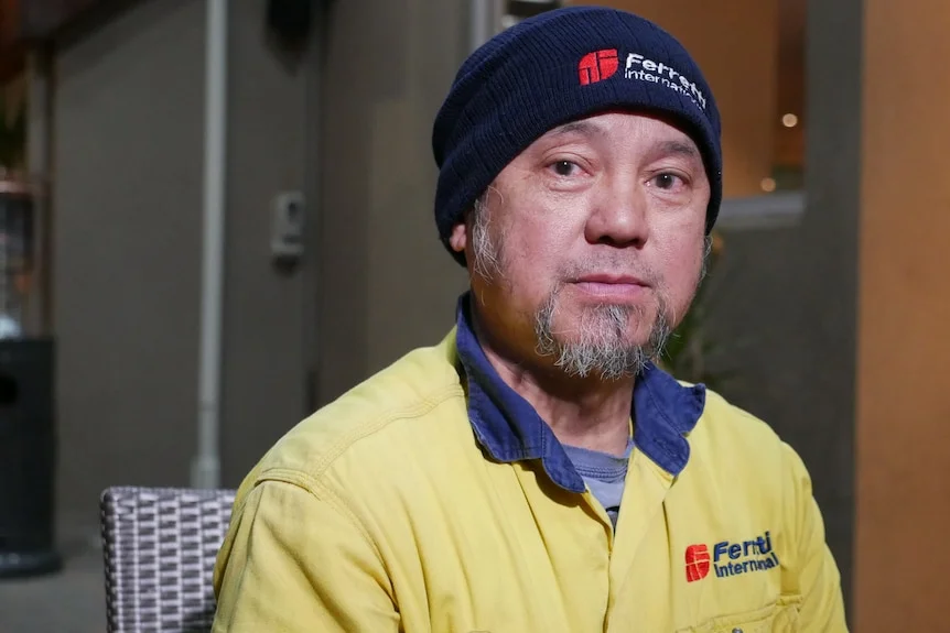 A man in a yellow high vis shirt and a beany both of which say Ferretti International.