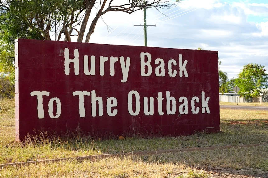 Sign that reads: Hurry back to the outback in Cloncurry. The sign is red with white words.