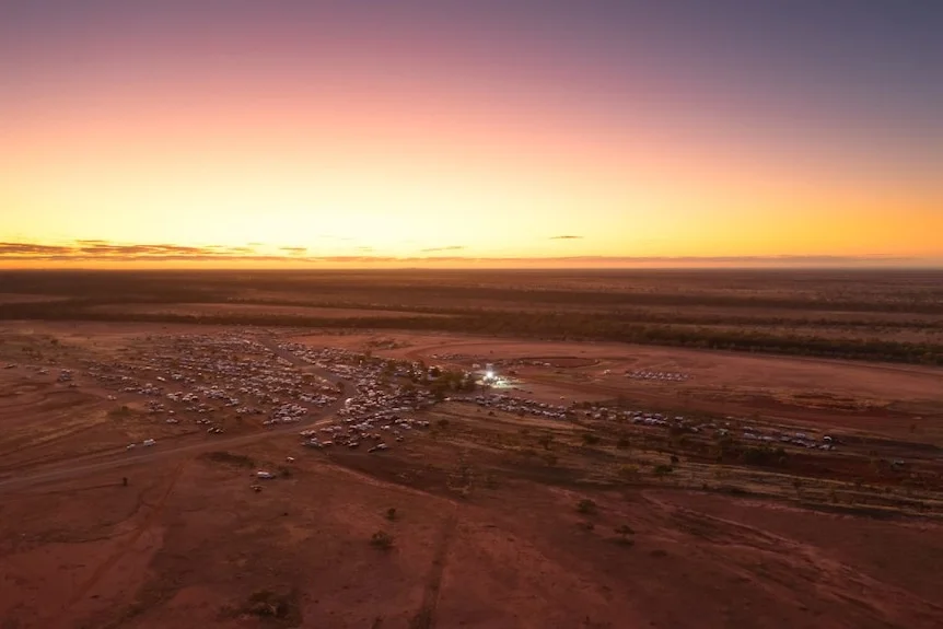 An aerial view of a small outback town in the middle of desert at sunset.