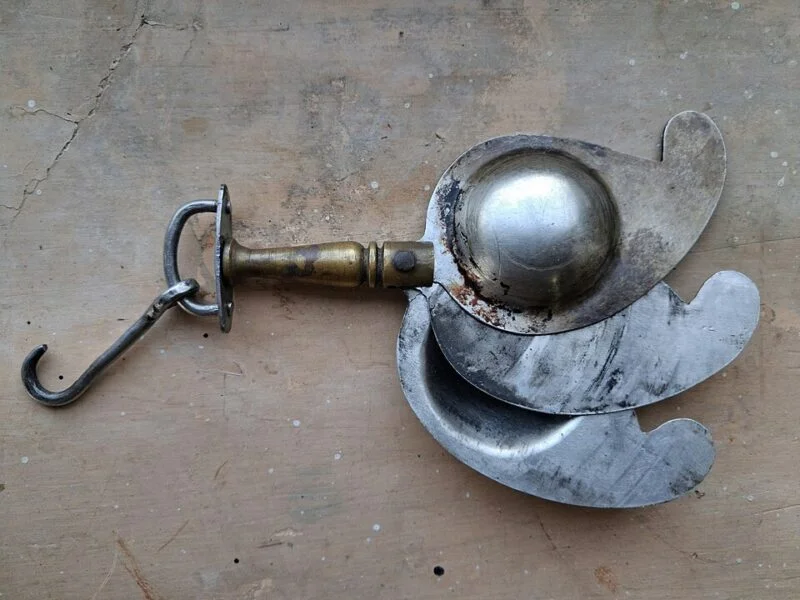 Kajrauti'-Kohl container with steel body and brass handle in the paisley shape. This container was made in the 20th century in Bihar, India. It has a flap in the middle and contains two sides in the form of a mango or paisley for depositing kohl. It is known as 'Kajrauti' in Angika language.