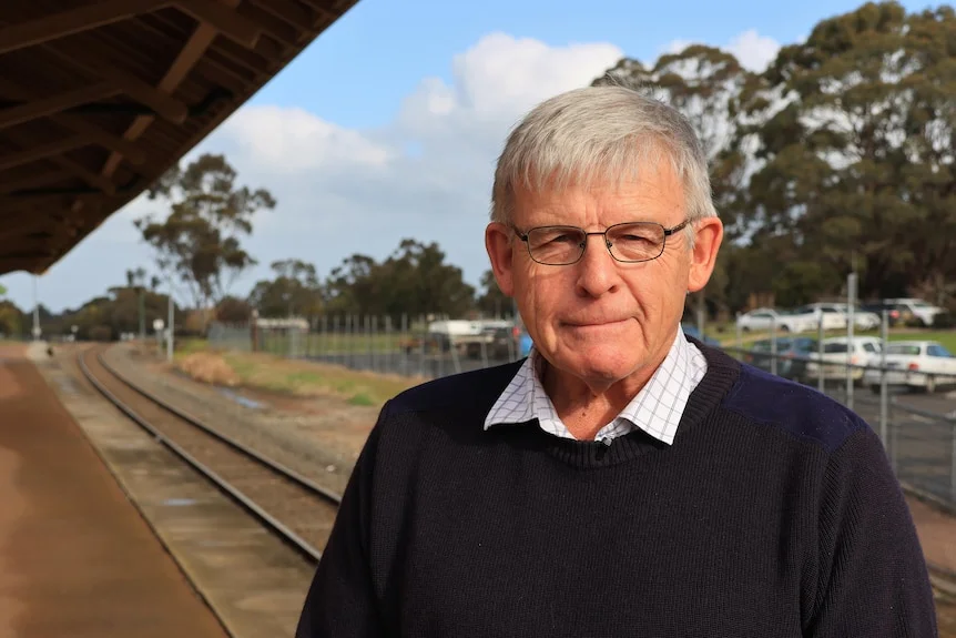 A man stands at a railway station