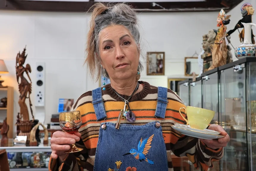 A woman holds up antique cups