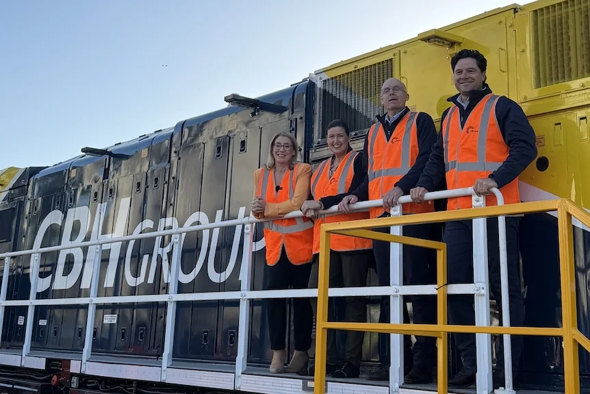 Four people stand alongside a train