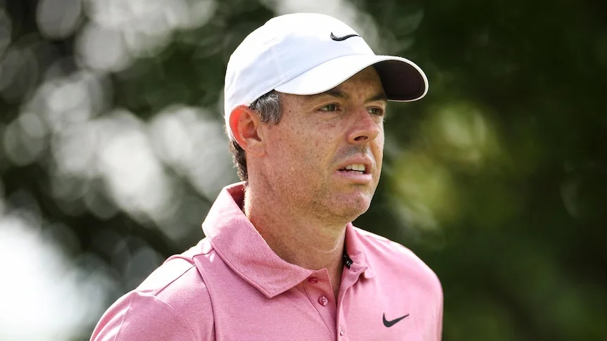 Rory McIlroy looks on while wearing white baseball cap