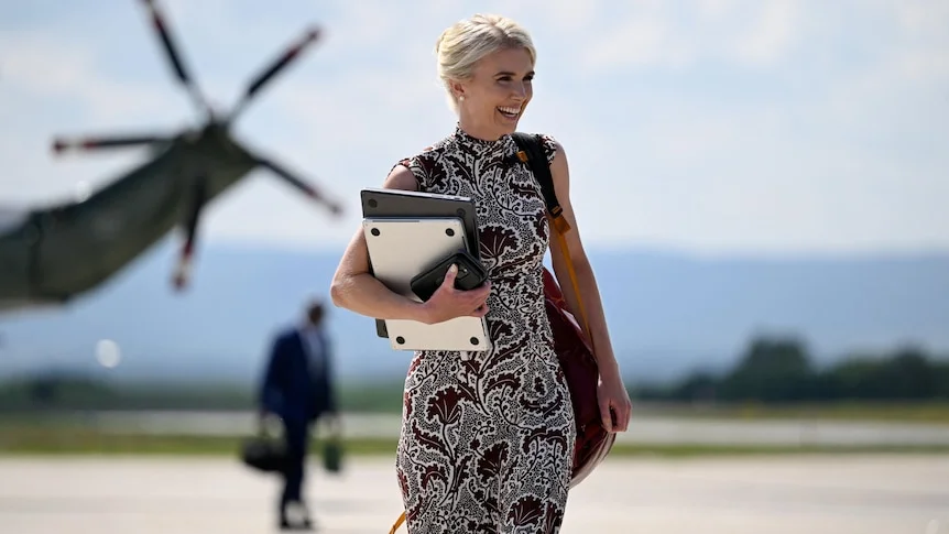 Natalie Harp carries a laptop and tech gear on an airport tarmac.