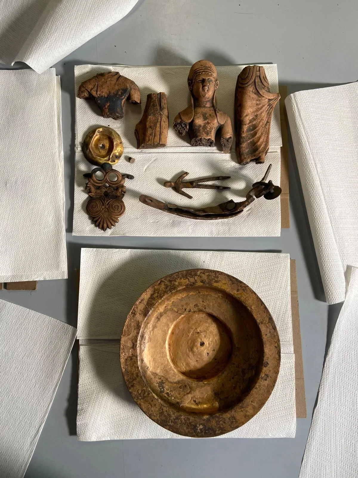 Images from an archaeological excavation showing bronze relics on paper towels.