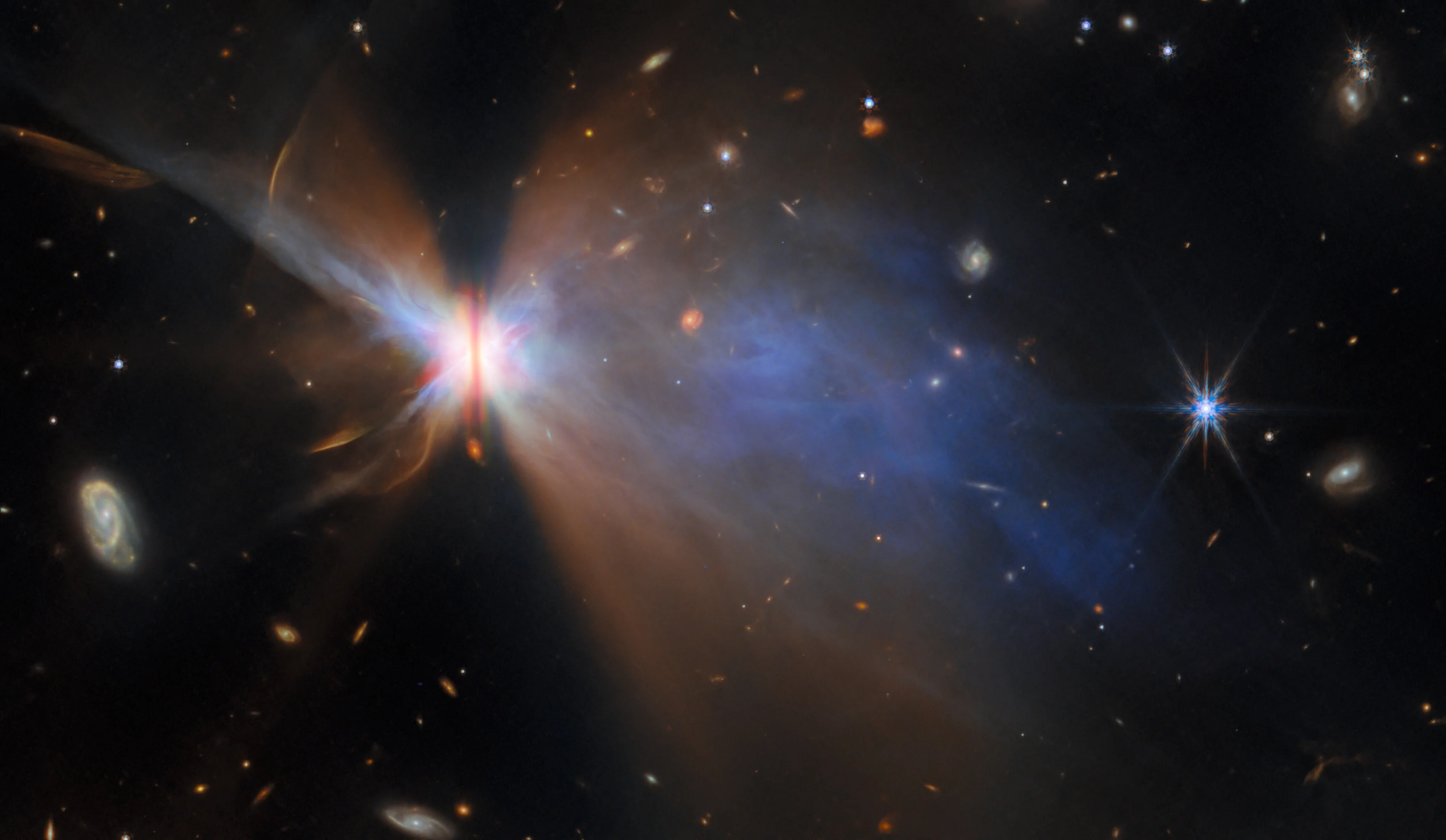 Hubble Space Telescope image shows a bipolar nebula with jets of gas and dust, surrounded by stars and distant galaxies against a dark background—offering a glimpse much like the JWST reveal that continues to expand our view of the universe.