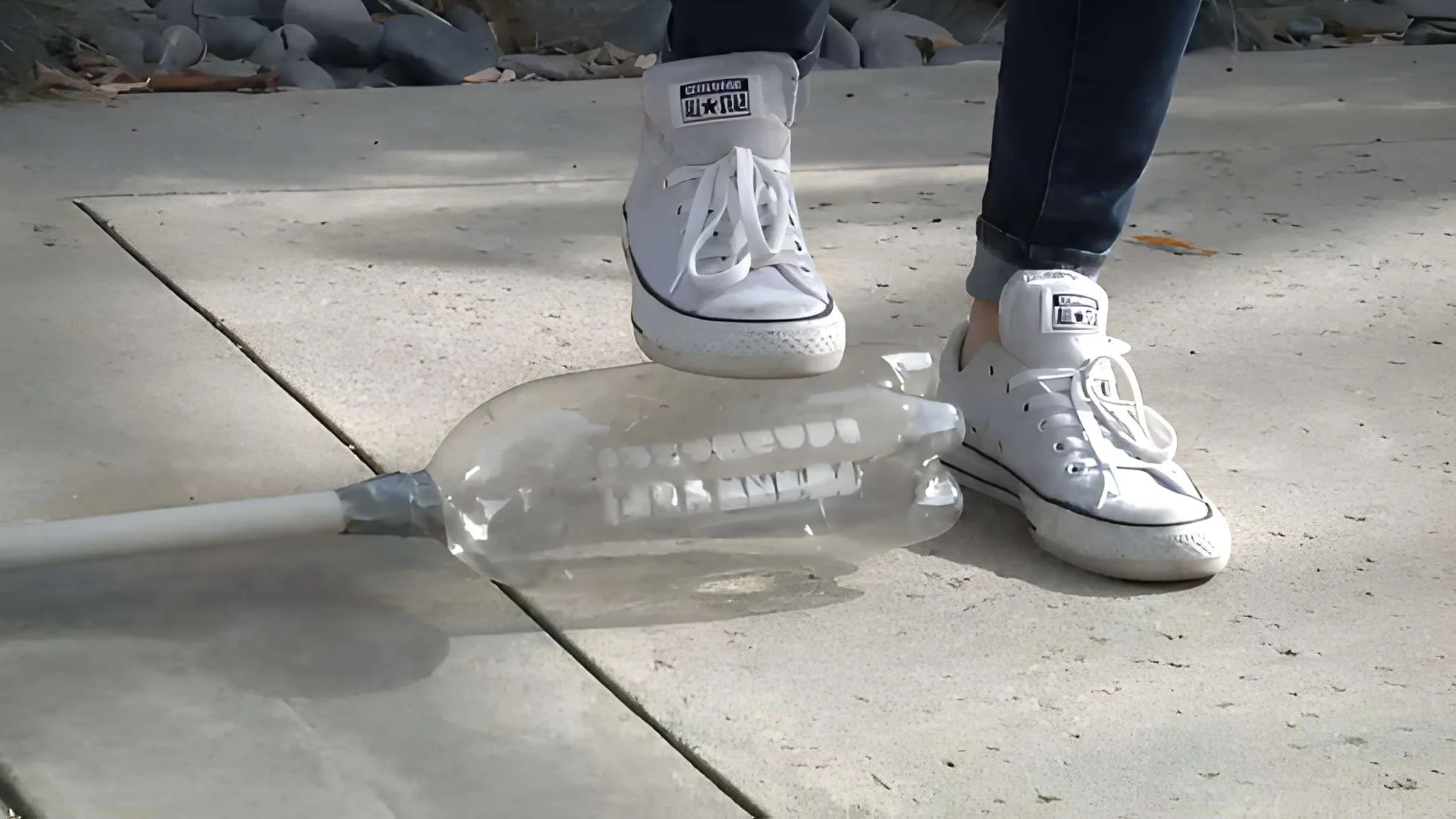 A foot on top of a plastic bottle, part of a homemade stomp rocket.