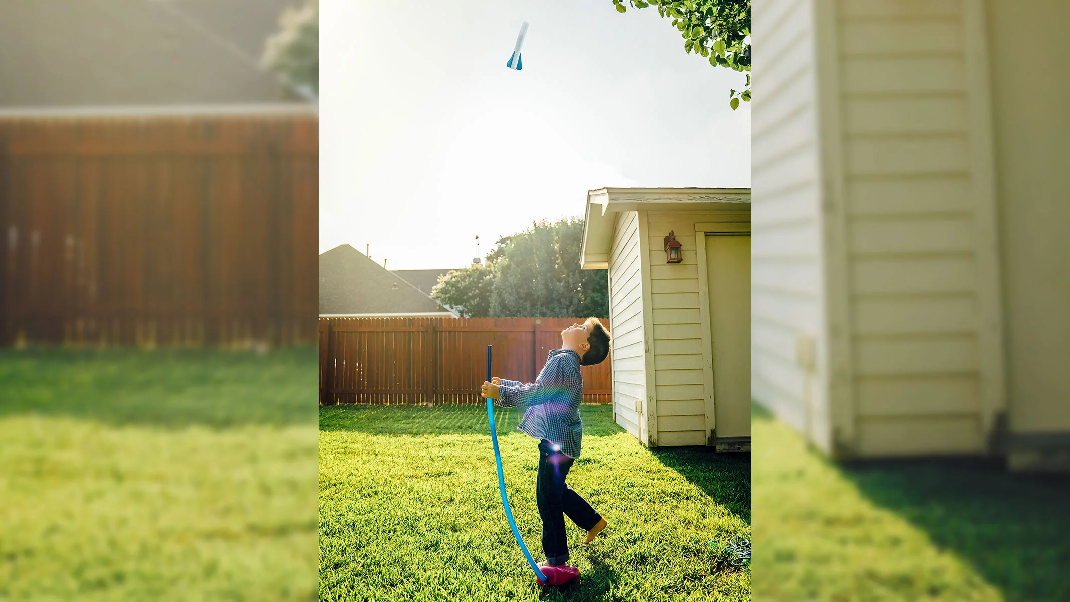 A boy looking up at the stomp rocket he's just launched, his foot still on the launcher.