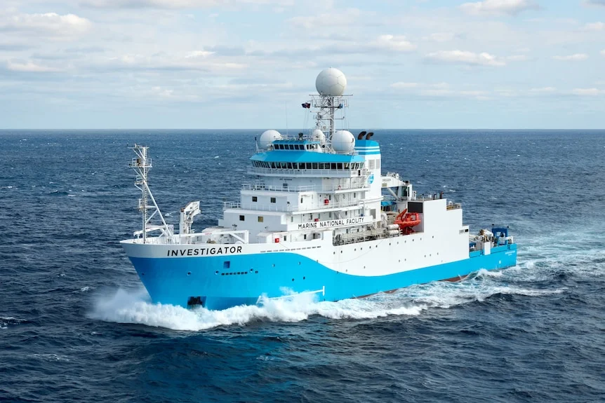 A blue and white ship cutting through waters