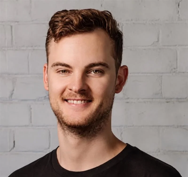 A man in a black shirt smiles at the camera