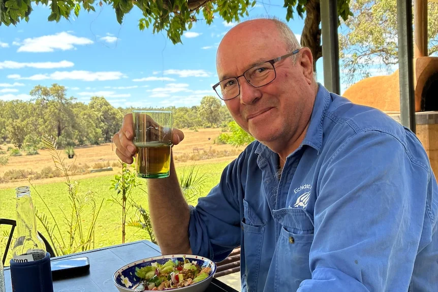 Ian Grant holds a glass of beer and smiles at the camera.
