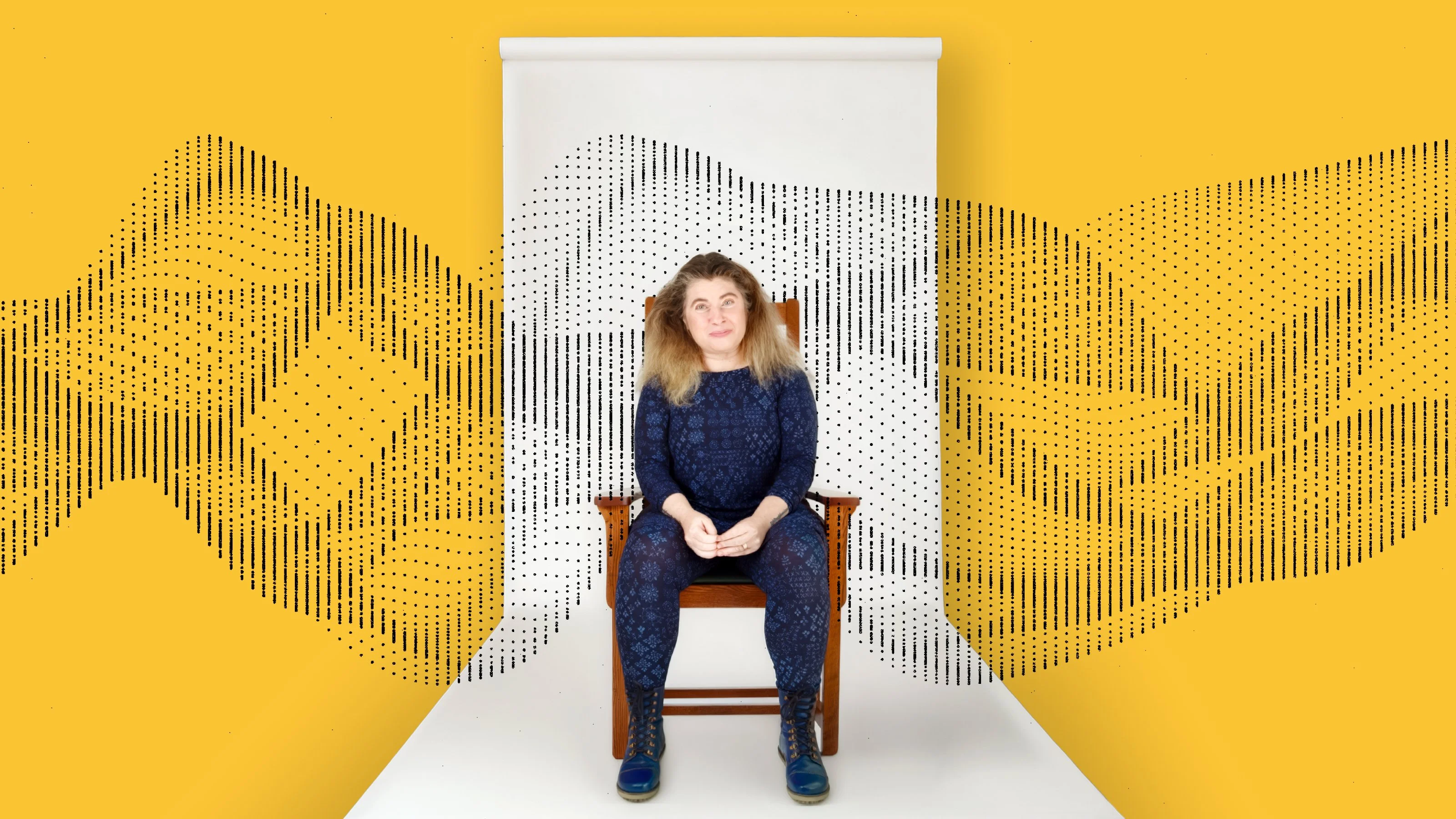 A person sits on a chair against a white backdrop with abstract black dotted patterns, set against a yellow background.