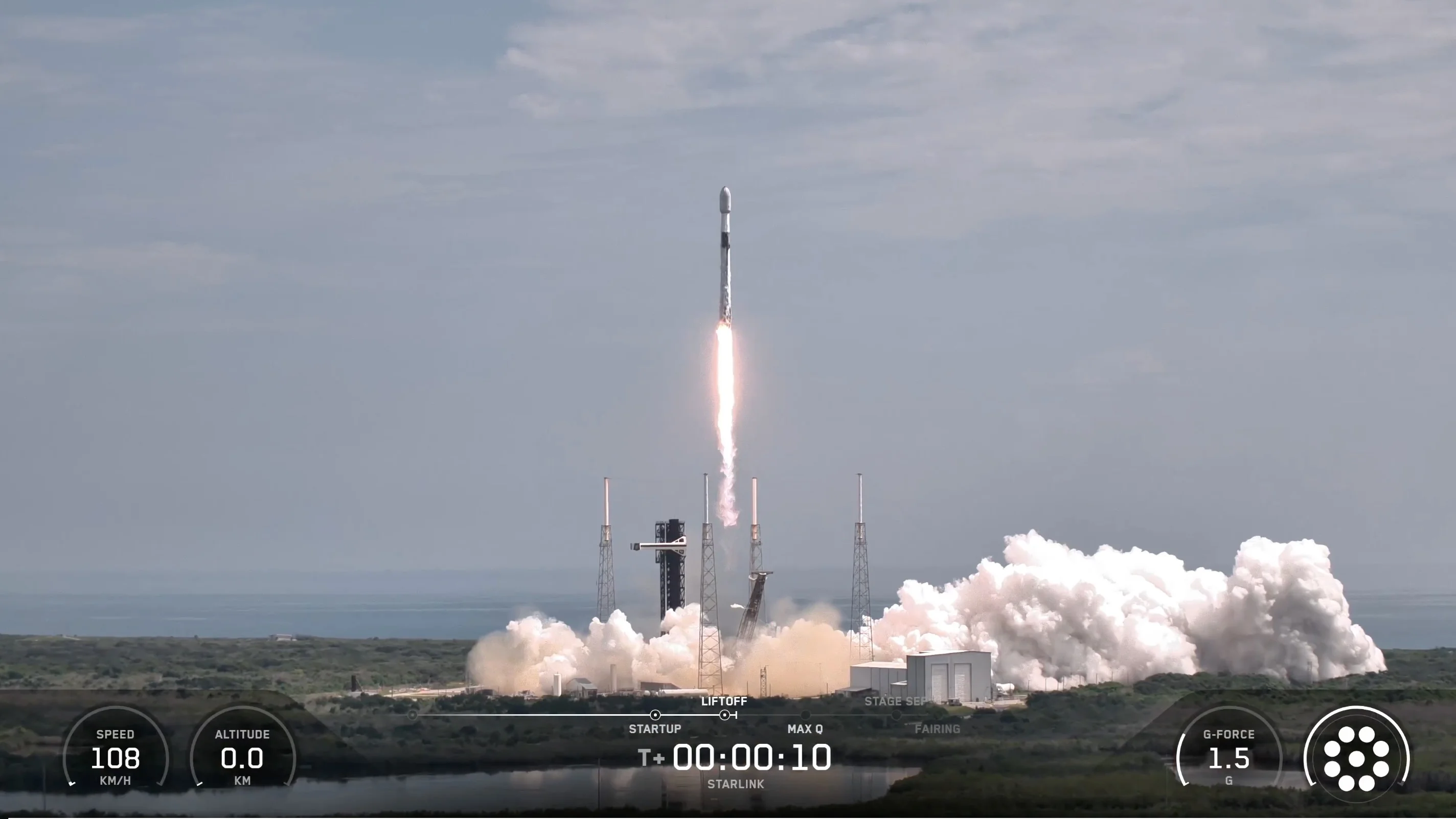 a black and white rocket launches from a seaside pad
