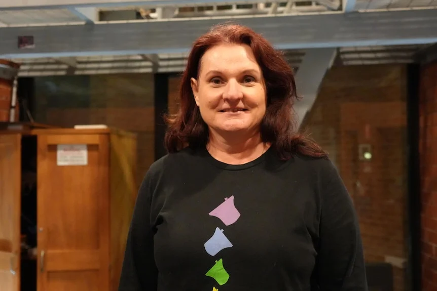 A woman wearing a jumper with a bell pattern poses for the camera.
