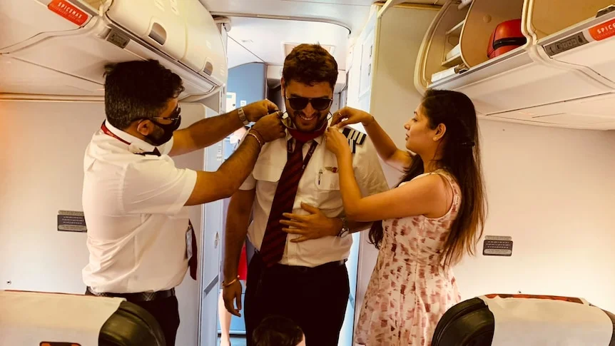 A pilot and wife help arrange new stripes on a captain's uniform.