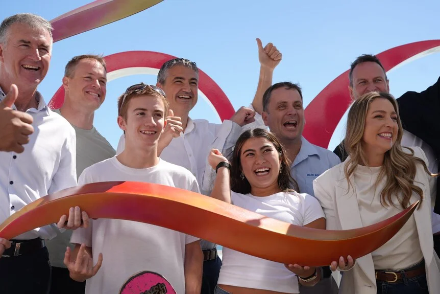 A group of people holding a piece of the Brisbane 2032 cockatoo emblem.
