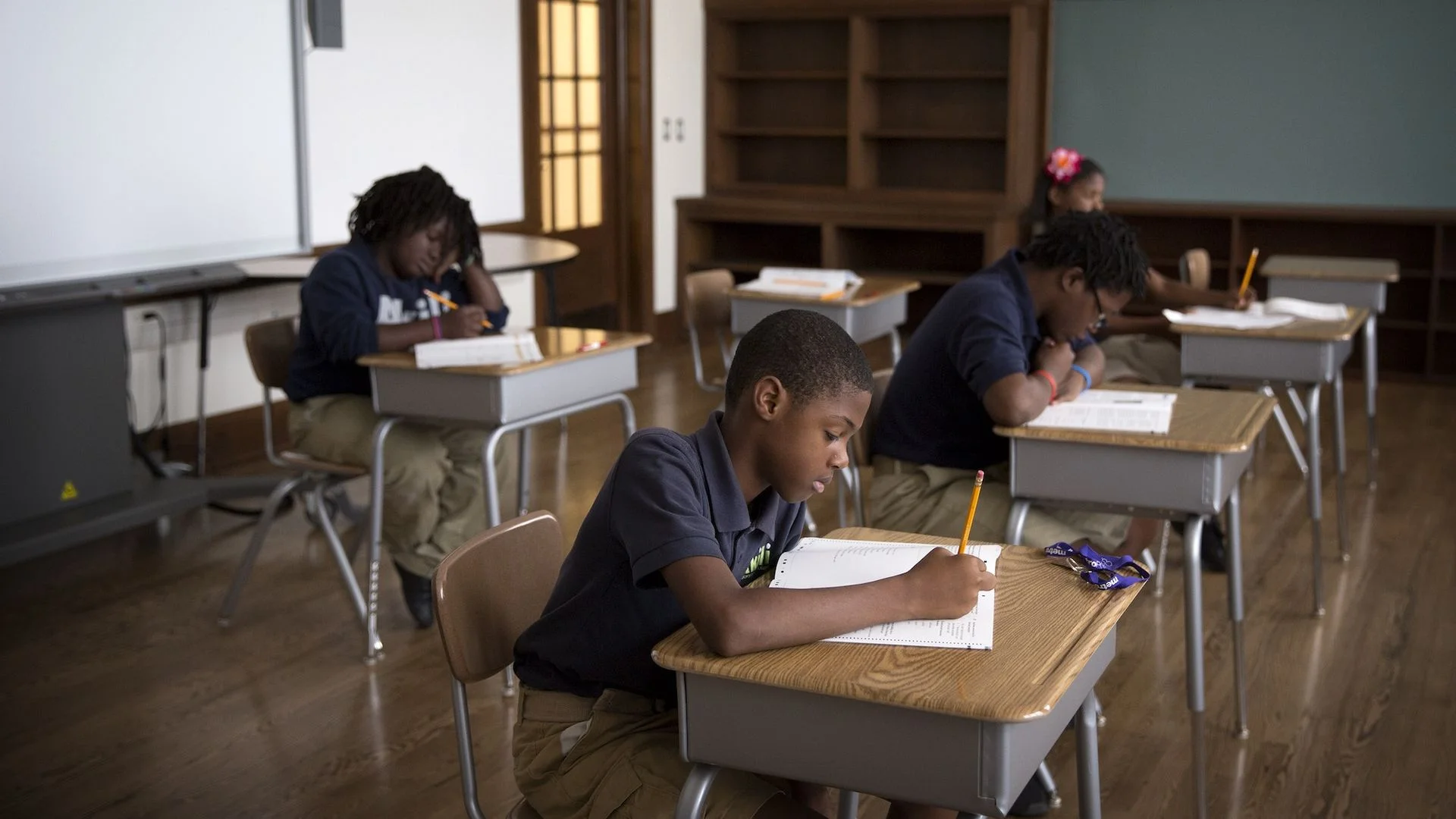 four kids at school desks taking tests