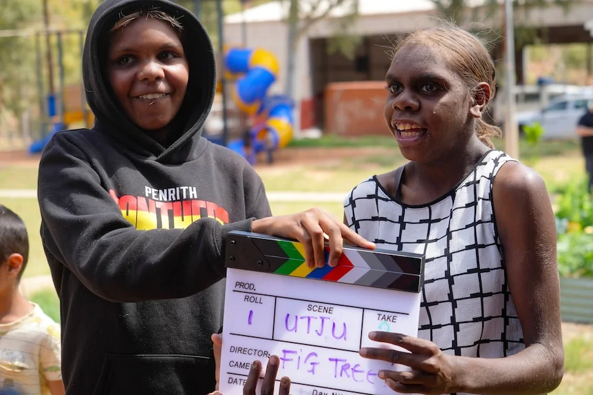 Geraldine and Sharnita mug for the camera while playing with a film clap board.