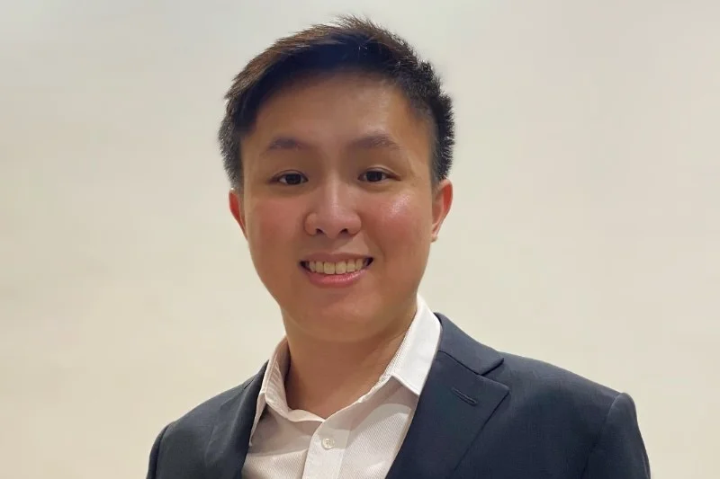 Marvin Tan has cropped brunette hair, he is wearing a suit and smiling at the camera.