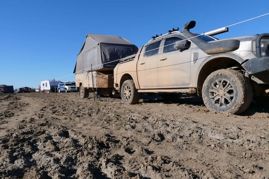 A vehicle moving slowly through mud at an outback festival