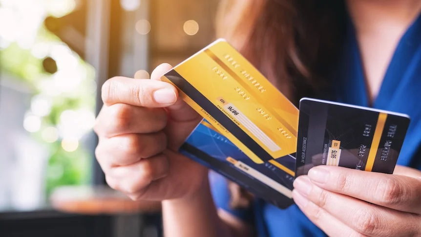 A person holds three credit cards with one hand and selecting one with the other. 