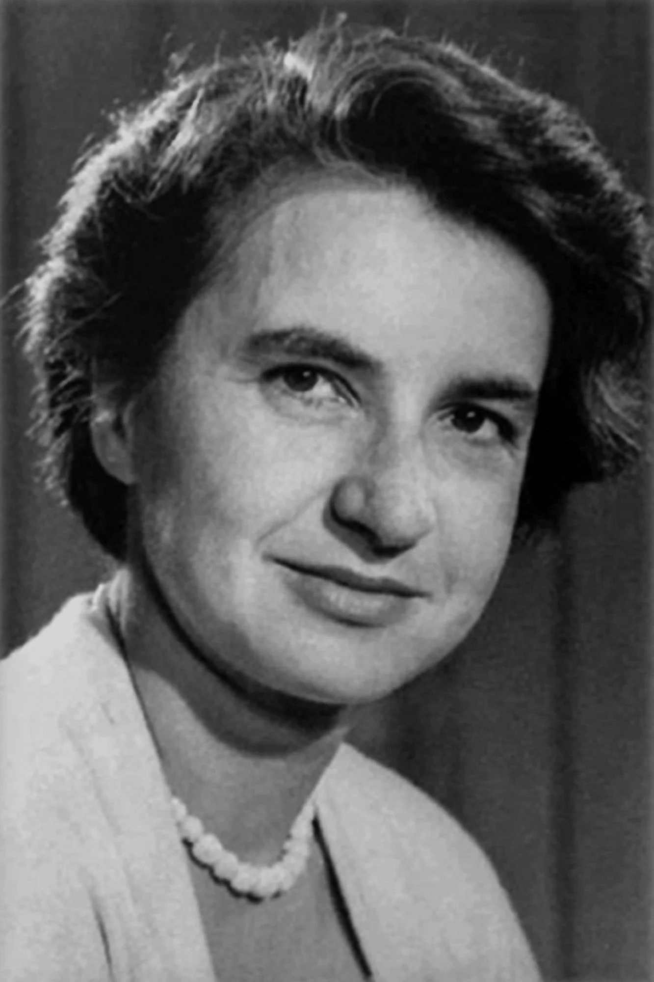 A black and white image of a woman with short hair wearing pearls.