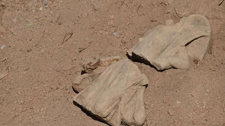 a statuette broken in two lies on the ground