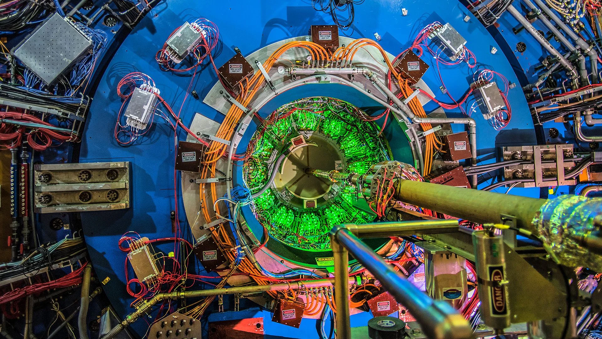 A close up of a circular collider with wires and pipes leading into it.