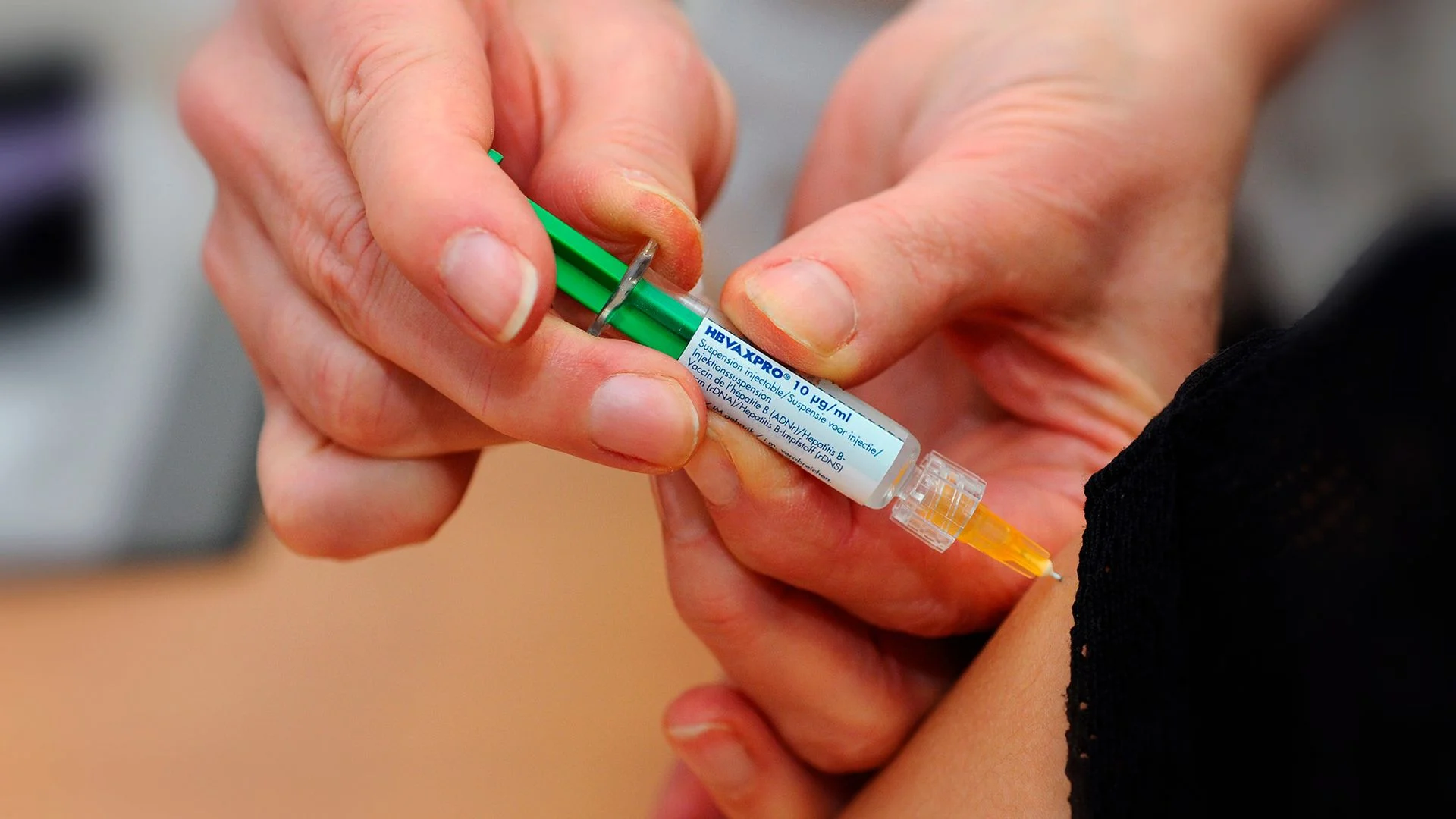 A close up of an orange liquid-filled syringe.
