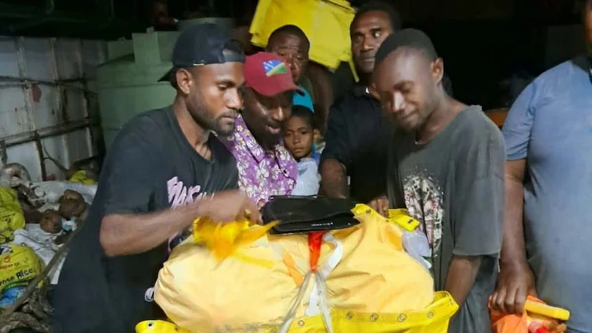 Men hold yellow raft bag.