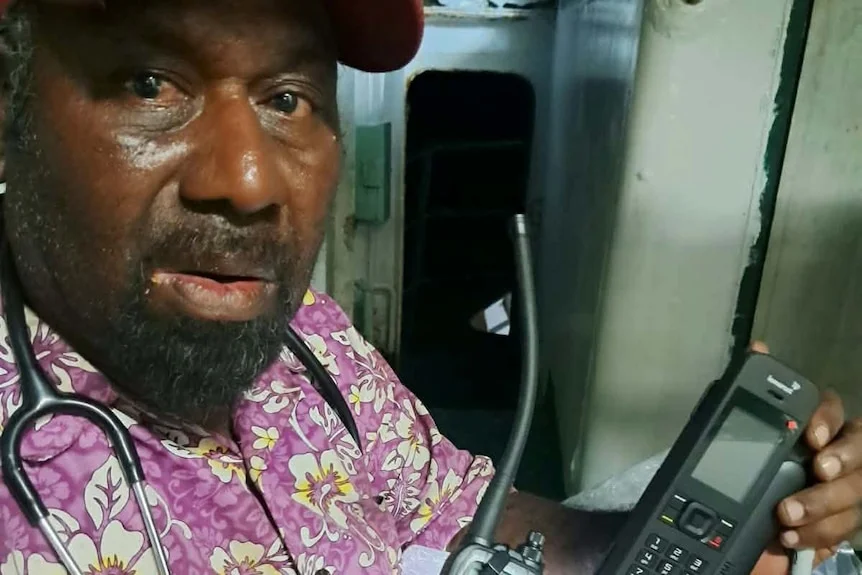 John Tua holding up communication equipment.