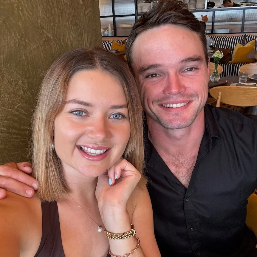 A man and woman taking a selfie at a restaurant table