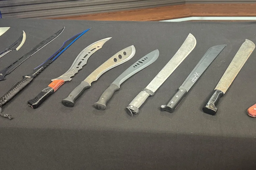 A table with lots of long knives laid out.