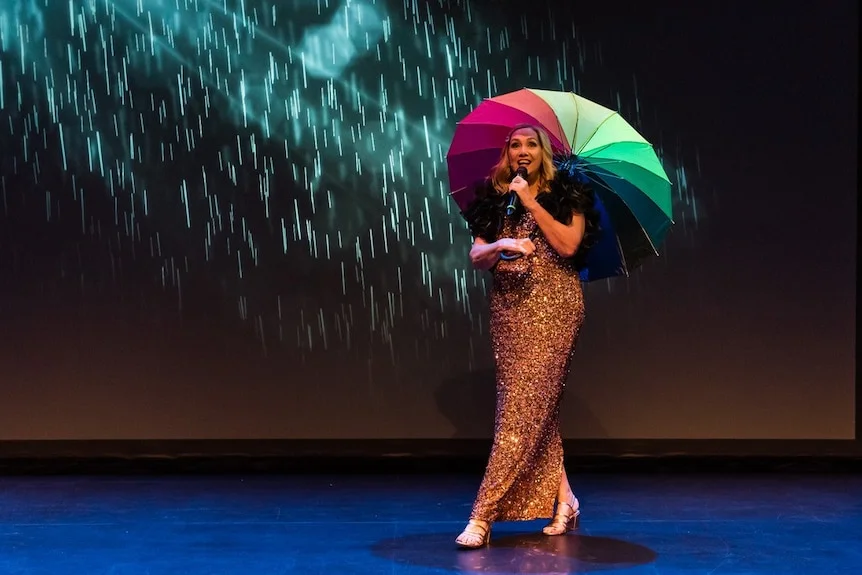 Jenny Woodward holding an umbrella on stage.