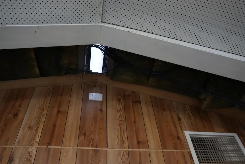 A high ceiling a hole in the roof and wires across it