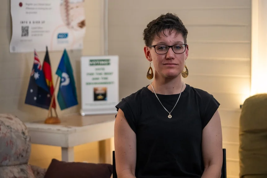 A woman with short hair sitting on a chair.