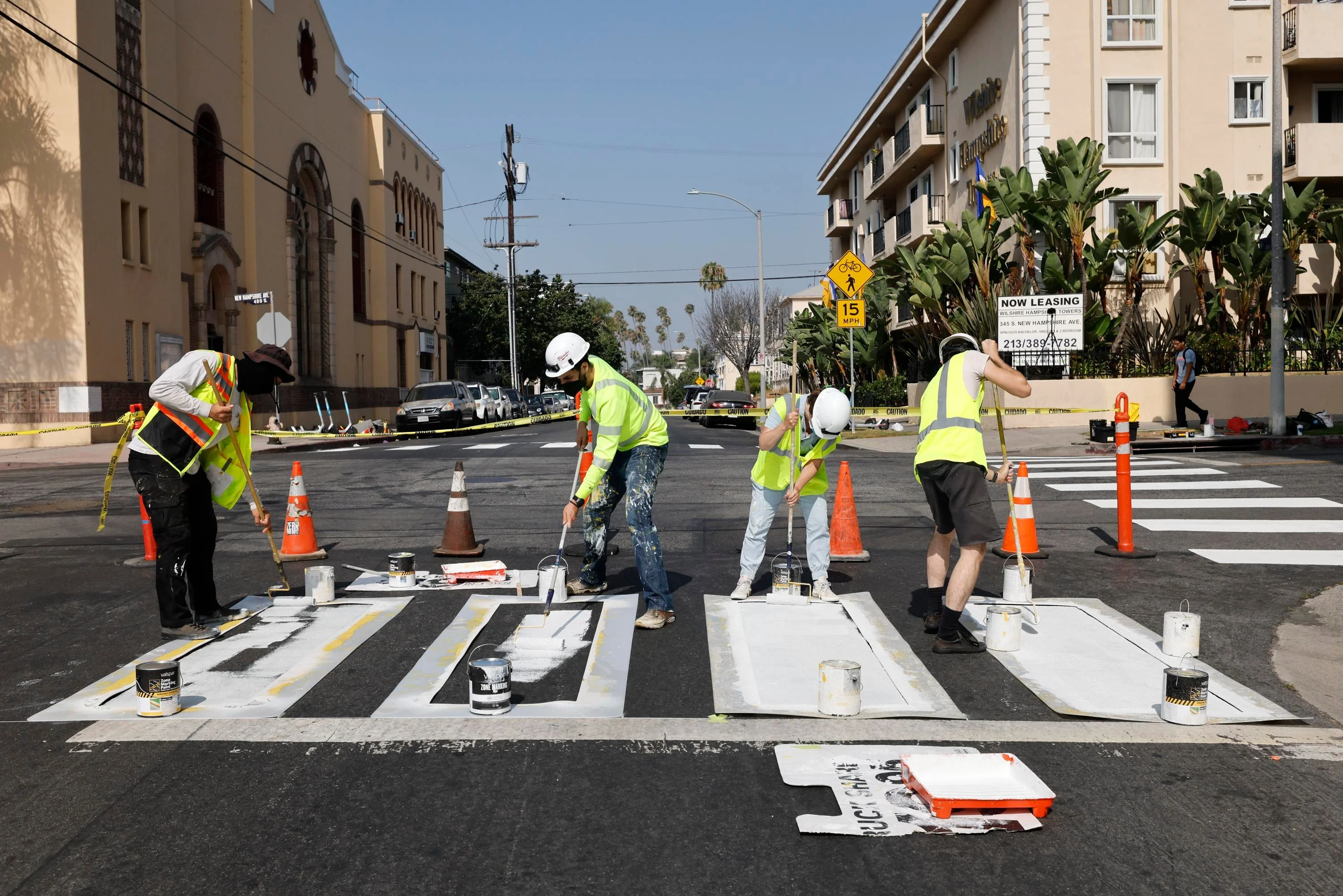 People in traffic vests paint a sidewalk